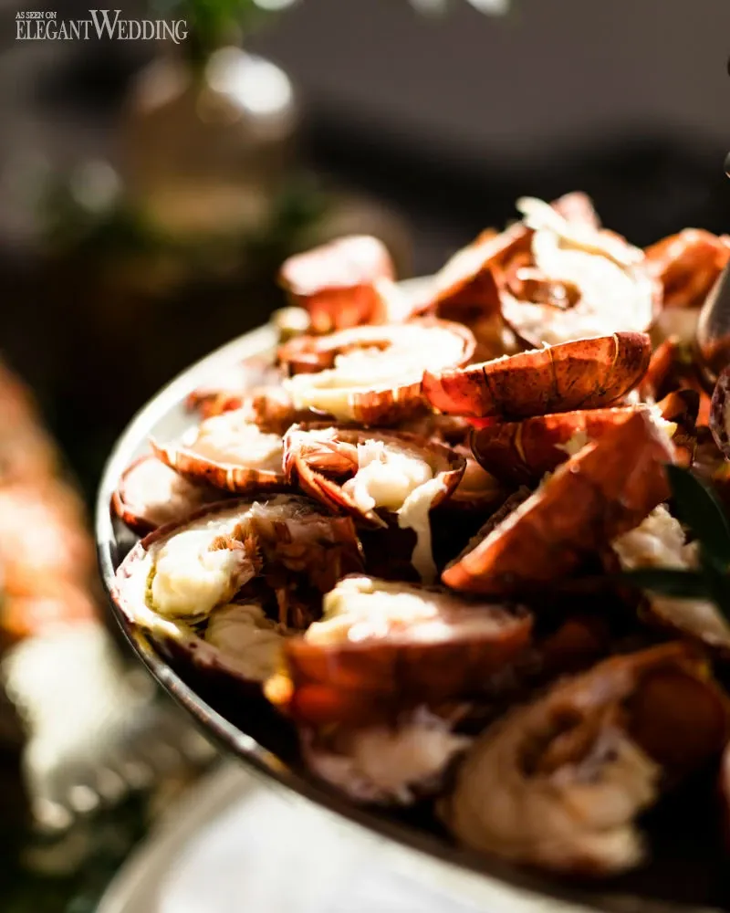 A beautifully arranged platter of lobster tails is showcased, glistening under ambient lighting, highlighting the luxurious catering options available at C’est Classique, a noted wedding venue in the Mariage Elegant directory. The image captures the succulent seafood in an elegant setting, suggesting an upscale dining experience for wedding celebrations.