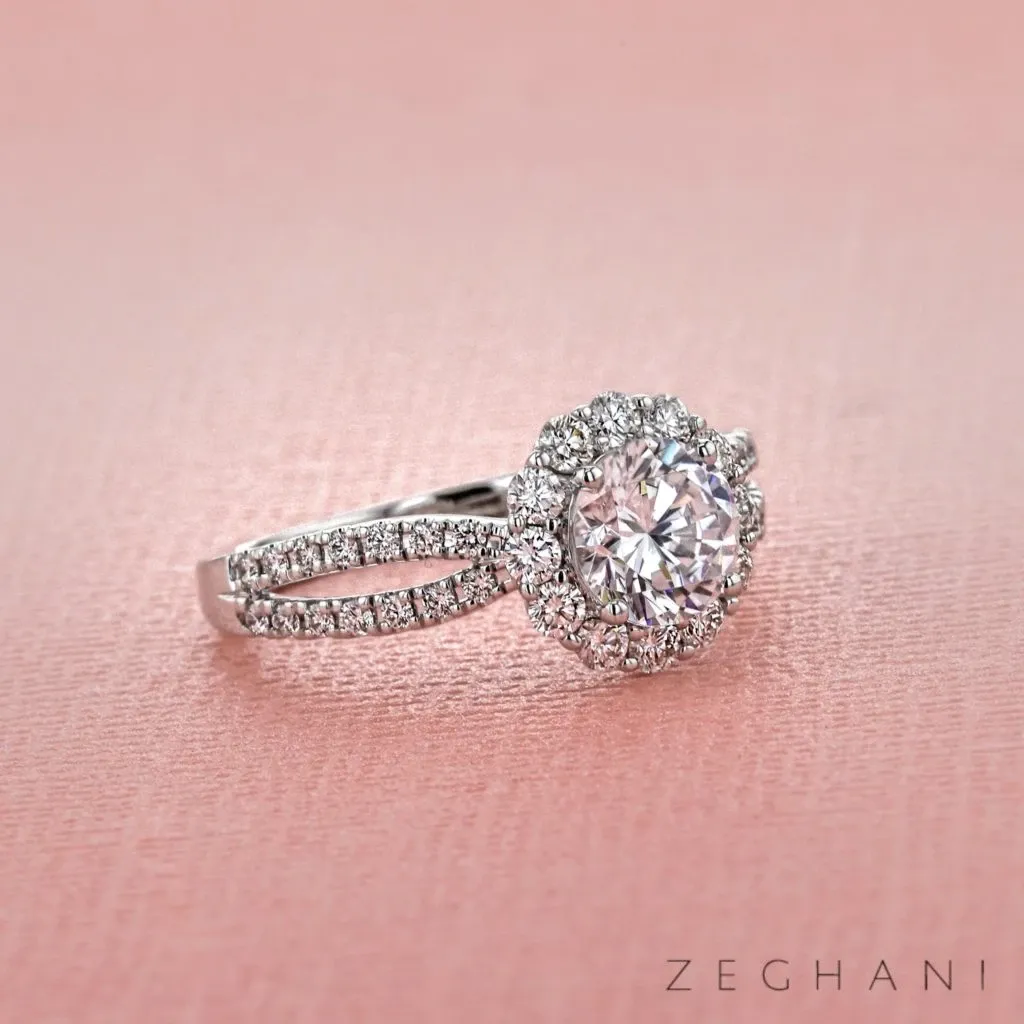This image features an exquisite diamond engagement ring from Bijouterie B. Serkos, categorized under Wedding Jewelry. The ring showcases a dazzling round-cut center diamond, surrounded by a halo of smaller round diamonds. The band is elegantly split and encrusted with additional diamonds, enhancing its sparkle against the soft pink textured background. This stunning piece exemplifies the fine craftsmanship and luxurious design offered by Bijouterie B. Serkos for wedding celebrations.