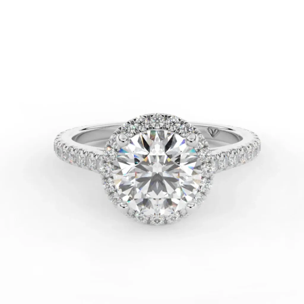 The image showcases a stunning engagement ring from Bijouterie La Voûte in the wedding jewelry category. The ring features a large, round brilliant-cut diamond set in the center, surrounded by a halo of smaller sparkling diamonds. The band is elegantly adorned with pavé-set diamonds, enhancing its luxurious appearance. This exquisite piece is perfect for adding elegance and sophistication to any wedding ensemble, highlighting the craftsmanship and quality offered by Bijouterie La Voûte.