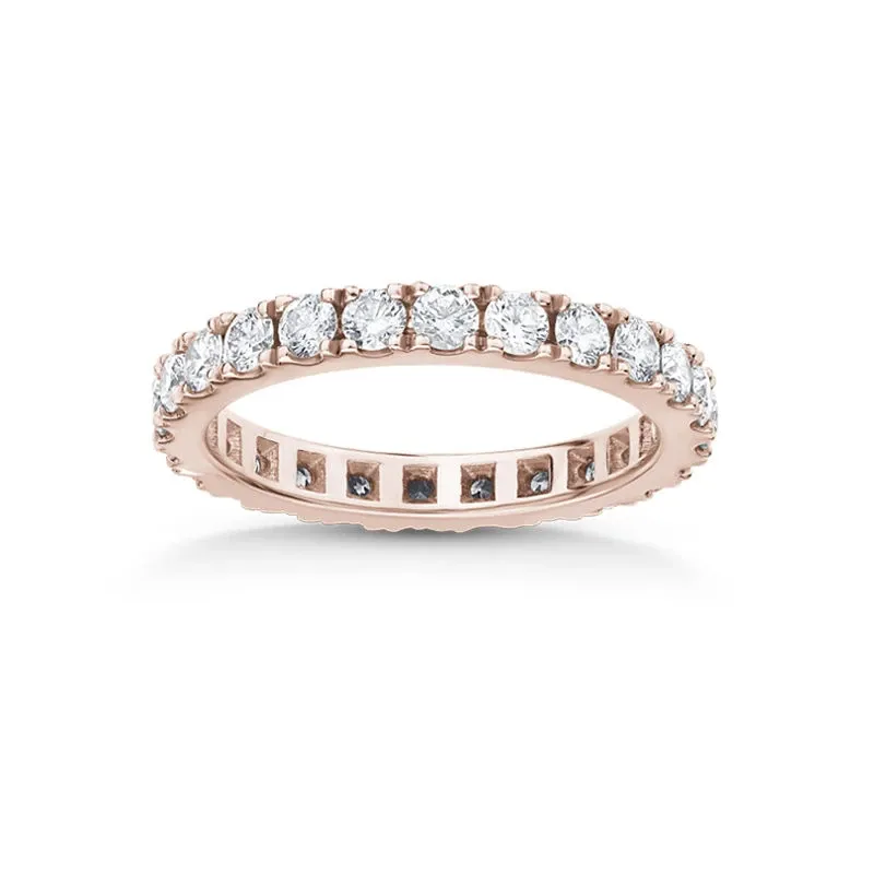 This image features a stunning rose gold eternity wedding band from Ex Aurum Jewelers, part of the Wedding Jewelry category. The ring is elegantly designed with a continuous row of brilliant round-cut diamonds meticulously set around the entire band. Each diamond sparkles brilliantly, reflecting exquisite craftsmanship, making it a perfect choice for a luxurious and timeless wedding accessory. The delicate rose gold setting enhances the diamonds' brilliance, creating a harmonious blend of elegance and sophistication, ideal for a special wedding day occasion.