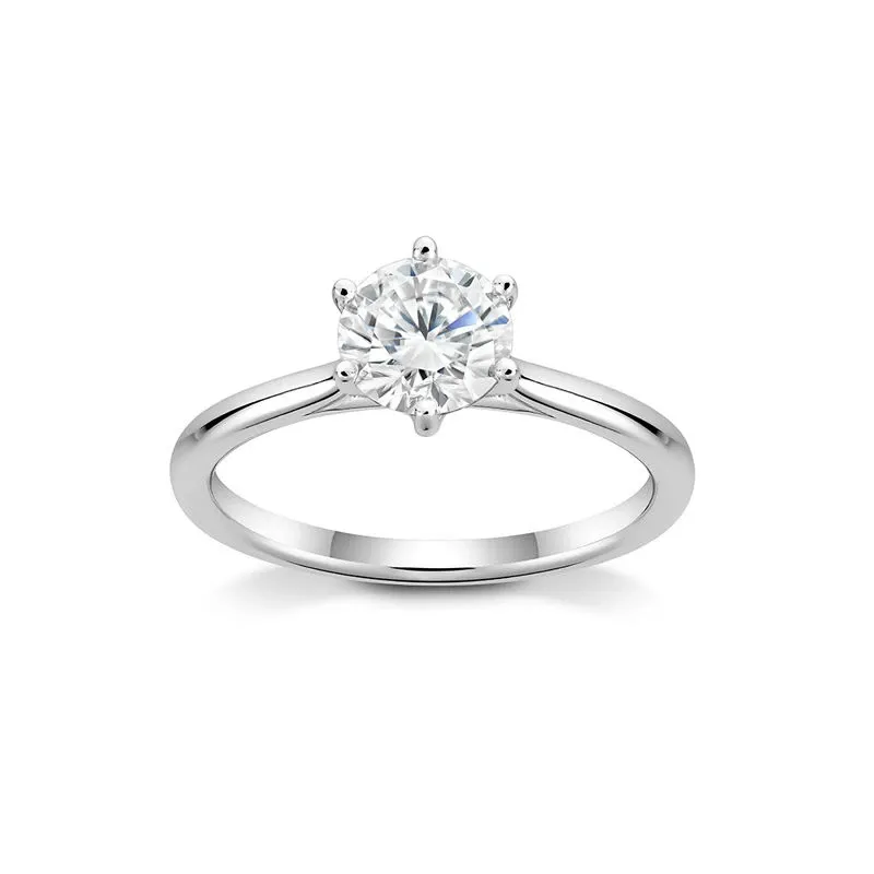 The image features a solitaire engagement ring from Ex Aurum Jewelers, categorized under Wedding Jewelry. The ring showcases a brilliant round-cut diamond held securely by six delicate prongs on a simple, polished white gold band. This elegant piece exemplifies classic bridal elegance, making it an ideal choice for brides seeking timeless sophistication in their wedding jewelry selection.