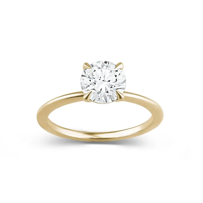 A stunning engagement ring from Ex Aurum Jewelers, featured in the wedding jewelry category of Mariage Elegant, Canada. The image showcases a classic solitaire ring with a brilliant round-cut diamond set in a sleek, polished gold band. The simplicity and elegance of the design make it a perfect choice for a timeless wedding accessory.