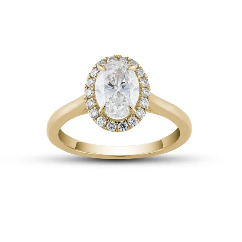 The image showcases a stunning engagement ring from Ex Aurum Jewelers, featured in the Wedding Jewelry category on Mariage Elegant, Canada. The ring displays a central oval diamond, elegantly set in a classic gold band. Surrounding the main stone is a halo of smaller round diamonds, enhancing the ring's brilliance and adding a touch of sophistication. This exquisite piece exemplifies fine craftsmanship and is perfect for a timeless wedding proposal.