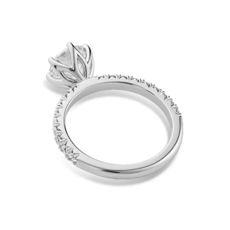 A close-up image of an elegant engagement ring designed by Ex Aurum Jewelers, a vendor specializing in wedding jewelry for Mariage Elegant, Canada. The ring features a detailed band with intricate, tiny triangular accents and a prominent, round-cut diamond set in a unique claw-like setting. This exquisite piece embodies sophistication and craftsmanship, ideal for couples seeking timeless jewelry for their special day.