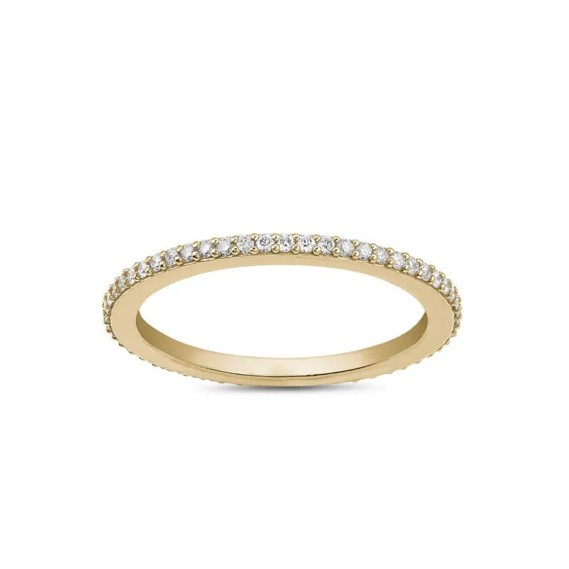 This image features a delicate gold wedding band adorned with small, sparkling diamonds encircling its exterior. The thin and elegant design is showcased against a plain white background, highlighting its intricate craftsmanship. This exquisite piece of wedding jewelry is from Ex Aurum Jewelers, a vendor listed on the Mariage Elegant site in Canada. The classic style of this ring makes it a timeless choice for couples looking to symbolize their commitment with sophistication and grace.