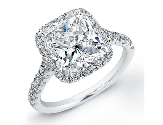 This image showcases a stunning piece from Eternal Diamonds, featured in the Wedding Jewelry category on Mariage Elegant, Canada. The focus is on an exquisite engagement ring with a radiant square-cut diamond as the centerpiece, beautifully complemented by a halo of smaller diamonds. The band is elegantly adorned with an array of diamonds, enhancing its luxurious appeal, perfect for symbolizing eternal love and commitment.