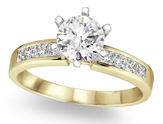 A beautiful gold engagement ring from Eternal Diamonds displayed in the wedding jewelry category, featuring a prominent round-cut diamond centerpiece held by six prongs. The band is elegantly adorned with a row of square-cut diamonds, enhancing the ring's luxurious appeal. Perfect for couples seeking timeless and sophisticated elegance for their wedding in Canada.