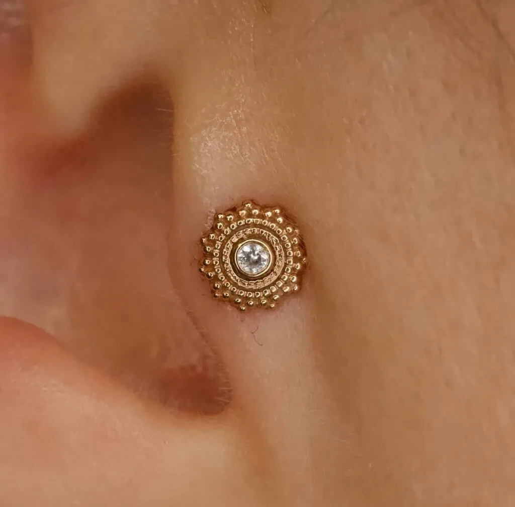 Un élégant piercing d'oreille en or avec un délicat motif floral et une pierre précieuse scintillante est présenté, mettant en valeur l'expertise de Paradise Montreal dans la catégorie Beauté pour le mariage sur Mariage Elegant, Canada. Ce bijou raffiné peut être un choix parfait pour ajouter une touche de glamour aux mariages.