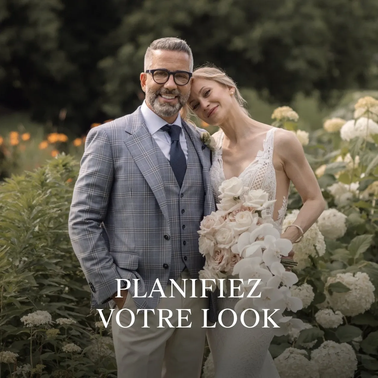 A couple elegantly poses outdoors, showcasing a sophisticated wedding style. The groom is wearing a refined Surmesur tuxedo, featuring a light grey plaid jacket, paired with a white shirt, navy tie, and dark trousers, perfectly suited for wedding events. The bride, in a delicate white lace gown, lovingly leans her head on his shoulder while holding a bouquet of blush and white flowers. They are standing amidst lush greenery and white hydrangeas. The image highlights the craftsmanship and style offered by Surmesur in the wedding tuxedo category, capturing a moment of elegance and romance. The text on the image reads 'Planifiez Votre Look,' suggesting the importance of planning a tailored wedding appearance.