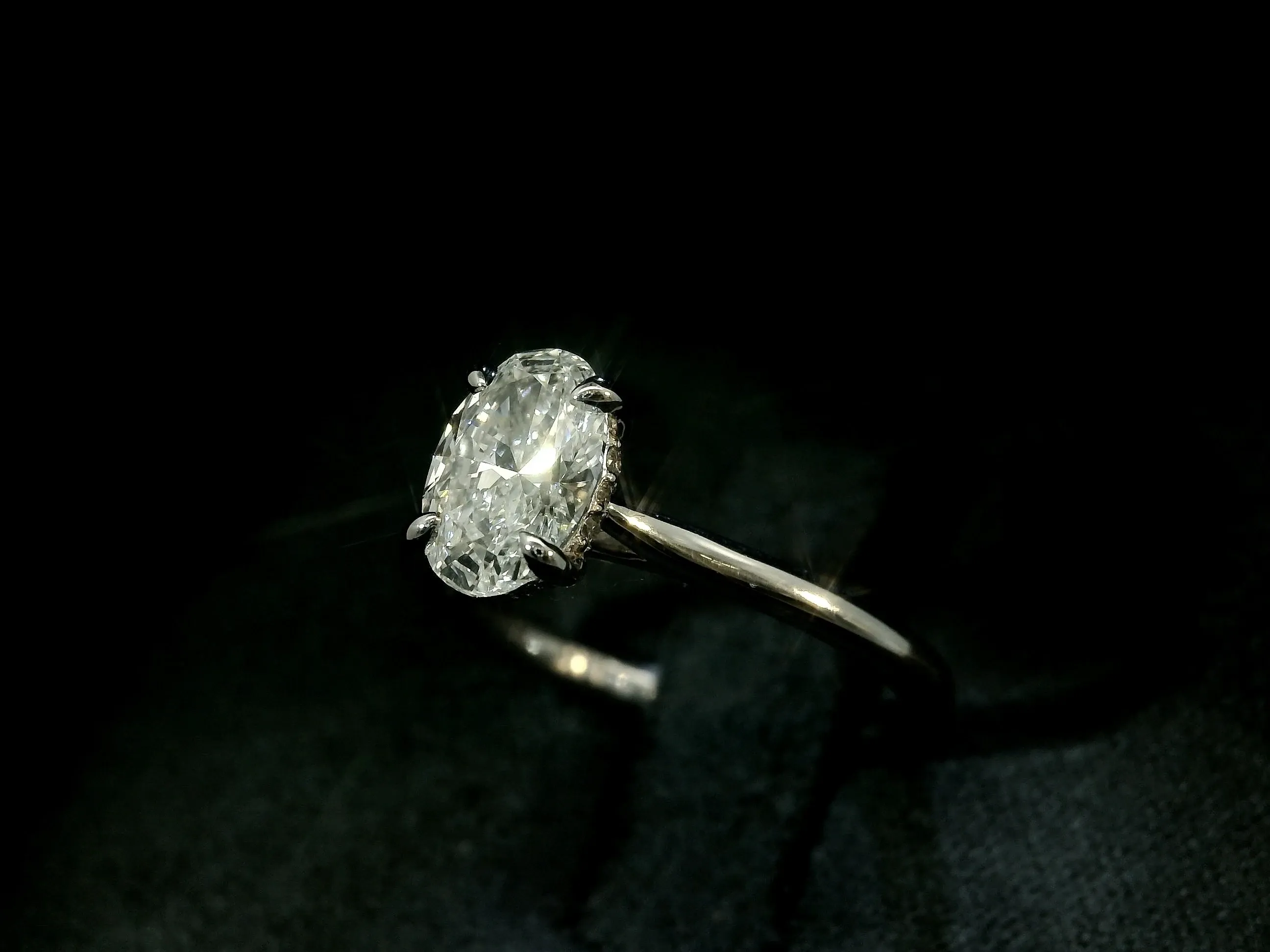 This image features a sparkling engagement ring from Angelica Jewellers, a premier vendor in the Wedding Jewelry category for Mariage Elegant in Canada. The ring showcases a dazzling oval-cut diamond set in a sleek, elegant band with a prong setting, which captures and reflects light beautifully. Perfectly embodying elegance and sophistication, this ring serves as an exquisite choice for those planning a timeless wedding.