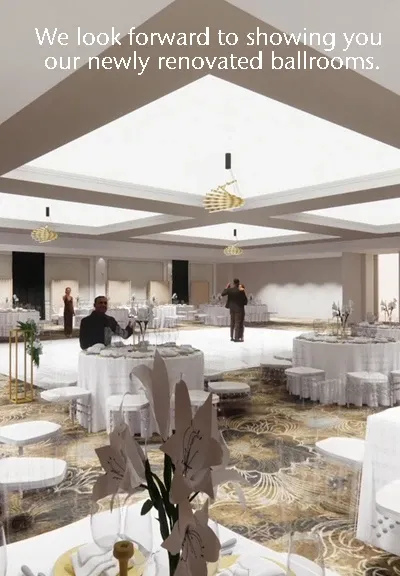 The image showcases the interior of a stylish wedding venue at Le Châteaubriand, categorized under wedding venues. The space features newly renovated ballrooms, with elegantly set tables draped in white linens and adorned with floral centerpieces. The room is illuminated by modern chandeliers, highlighting the detailed carpet pattern. Staff members can be seen preparing the venue, suggesting a welcoming and professional environment for weddings and events.