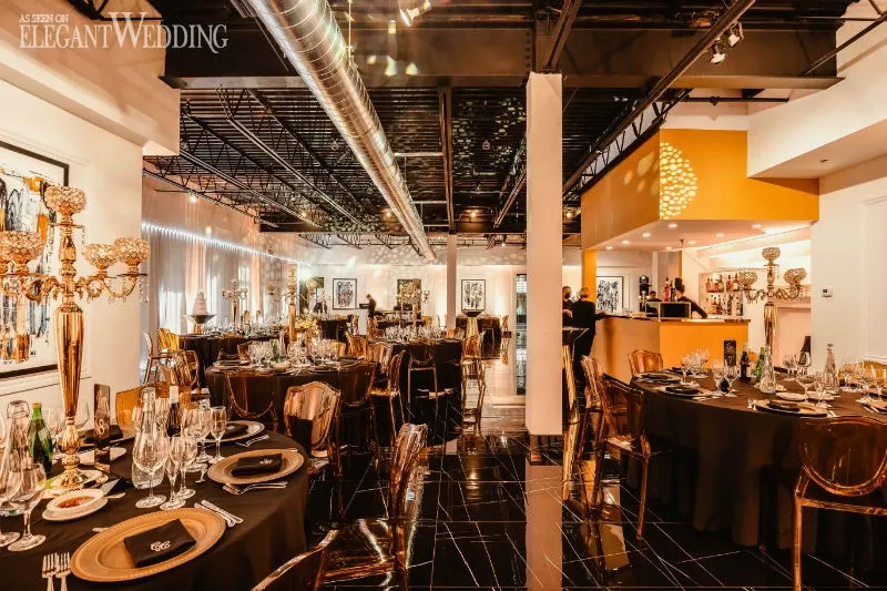 This image features the interior of a sophisticated wedding venue provided by the vendor C’est Classique, listed in the Wedding Venues category on Mariage Elegant in Canada. The venue is elegantly decorated, showcasing tables set with fine china, crystal glassware, and gold-toned centerpieces. The warm lighting and modern decor create an inviting and luxurious ambiance. The room's high ceiling and polished floors contribute to the contemporary style, making it an ideal setting for an elegant wedding celebration.