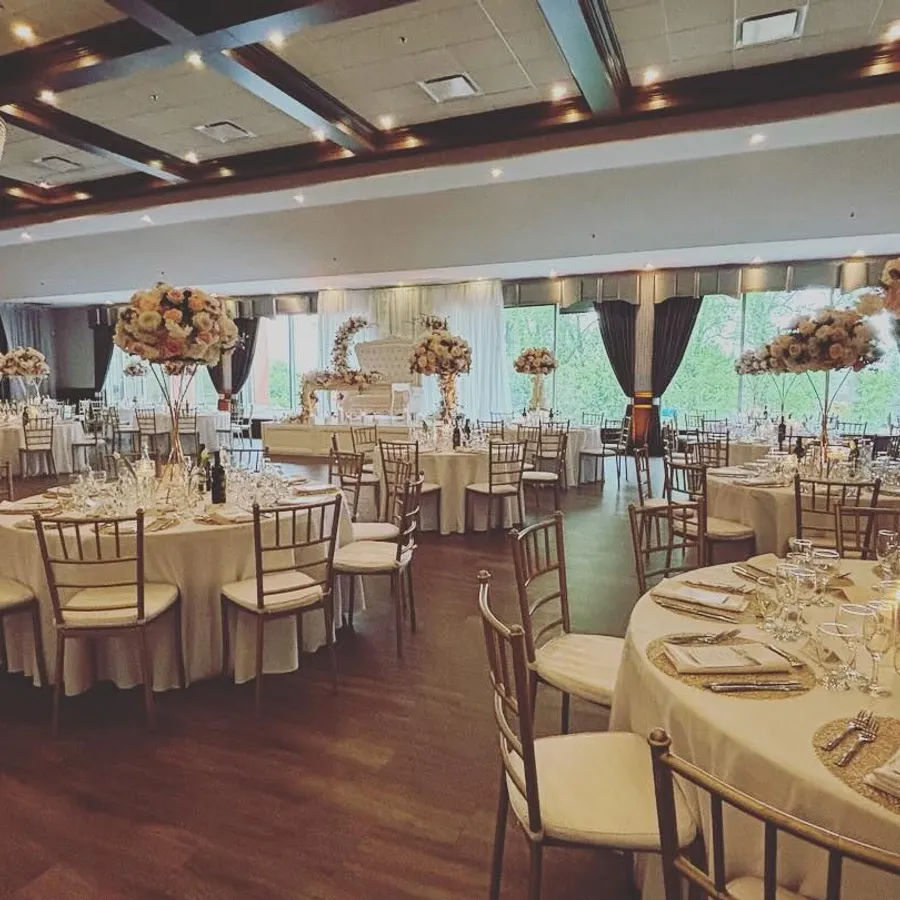 La salle de réception Plaza Rive Sud présente une ambiance élégante et sophistiquée, idéale pour un mariage. Les tables rondes sont élégamment dressées avec des nappes blanches et des arrangements floraux somptueux de roses et de fleurs pastel. Des chaises argentées entourent chaque table, ajoutant une touche de modernité. Un spectaculaire lustre en cristal suspendu au plafond ajoute une luminosité chaleureuse à la pièce spacieuse, mettant en valeur les rideaux élégants et les grandes fenêtres qui laissent entrer une lumière naturelle douce. Cette salle est particulièrement adaptée pour les célébrations de mariage sur mesure.