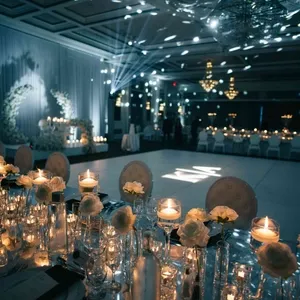 Salle de réception élégante chez Plaza Volare, mettant en valeur une décoration de mariage somptueuse avec une piste de danse centrale bien éclairée. Des chandelles et des fleurs blanches ornent les tables, créant une ambiance romantique et intime. Les lustres suspendus ajoutent une touche de glamour à l'éclairage tamisé, idéal pour un mariage sophistiqué en soirée. L'espace est aménagé pour accueillir de nombreux invités, offrant un cadre parfait pour célébrations et réceptions de mariage.