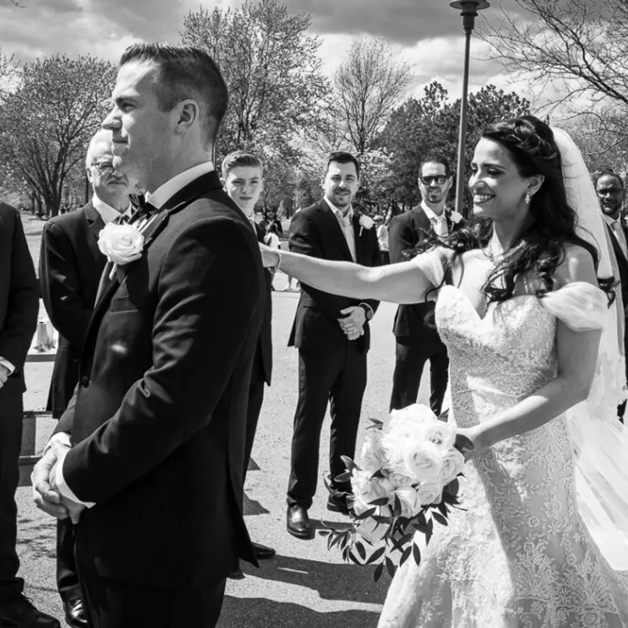 Dans cette image en noir et blanc, une mariée souriante touche doucement l