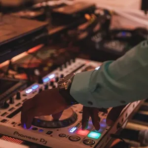 Un DJ anime une réception de mariage en manipulant les platines sur une console Pioneer DJ, entouré d'équipements audio. Les lumières colorées sur la console créent une ambiance festive. L'image souligne l'expertise de KNL Productions dans la catégorie Animation, mettant en avant leur capacité à offrir un environnement musical dynamique pour les mariages au Canada.