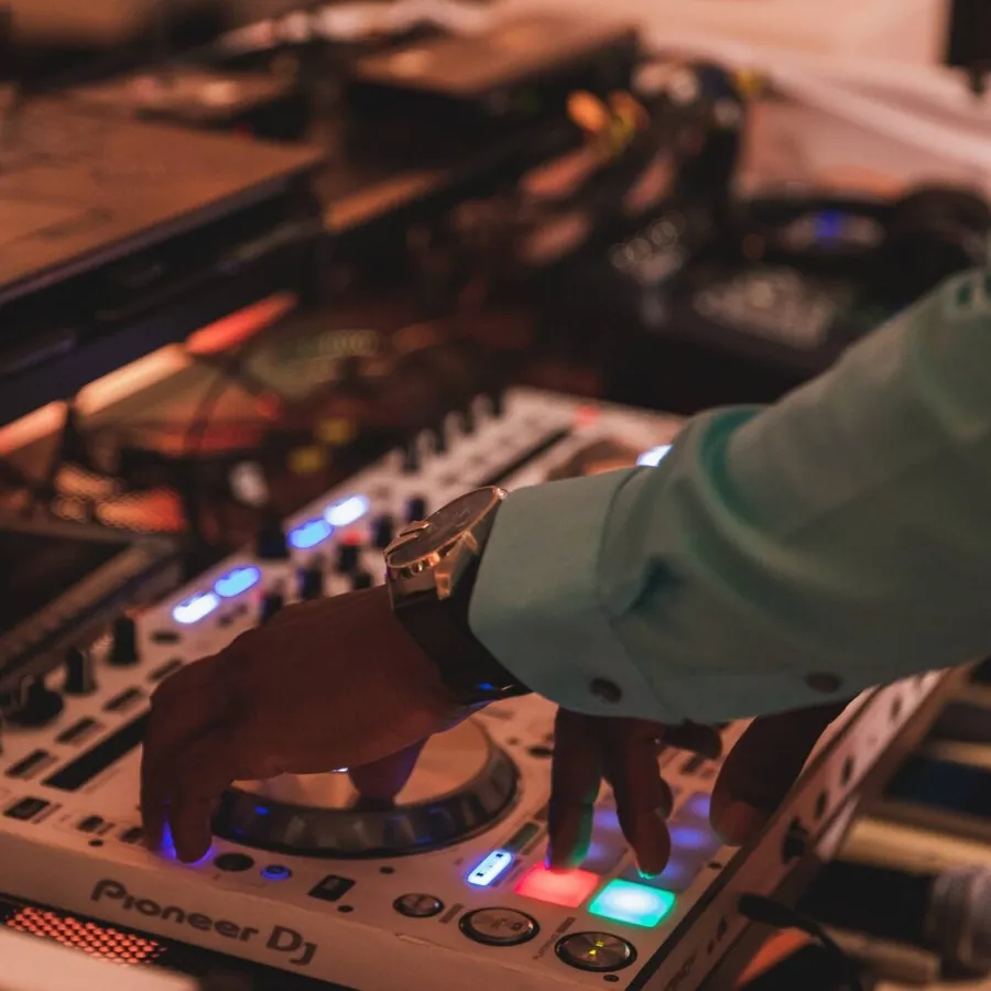 Un DJ anime une réception de mariage en manipulant les platines sur une console Pioneer DJ, entouré d