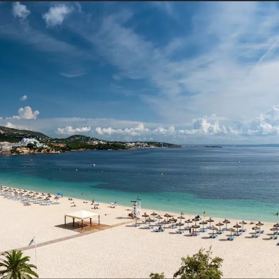 La photo montre une magnifique plage de sable fin bordée par des eaux turquoise, idéale pour un mariage à destination. Des parasols et des chaises longues sont soigneusement disposés, offrant un cadre idyllique pour les mariages organisés par Voyage Club Evasion, spécialiste du mariage à destination. À l