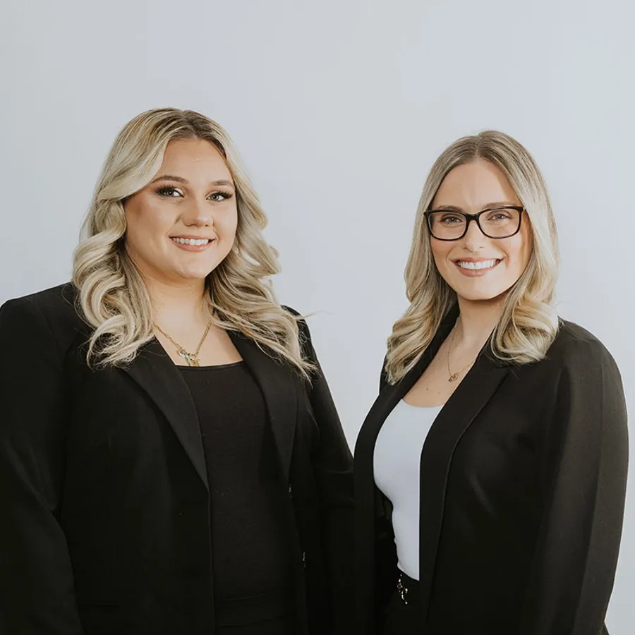 Deux femmes souriantes, associées à Di Event Sisters, spécialisées en tant que planificateurs de mariage, se tiennent côte à côte. Elles portent toutes les deux des vestes noires professionnelles, l